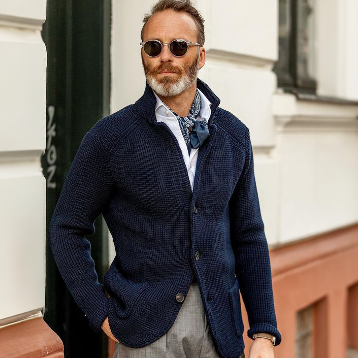 Man wearing navy knit cardigan outdoors with sunglasses, lifestyle shot