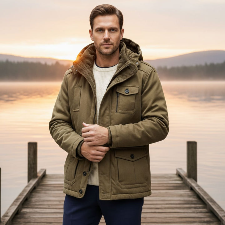 Man wearing Landon olive parka jacket outdoors near a lake at sunset